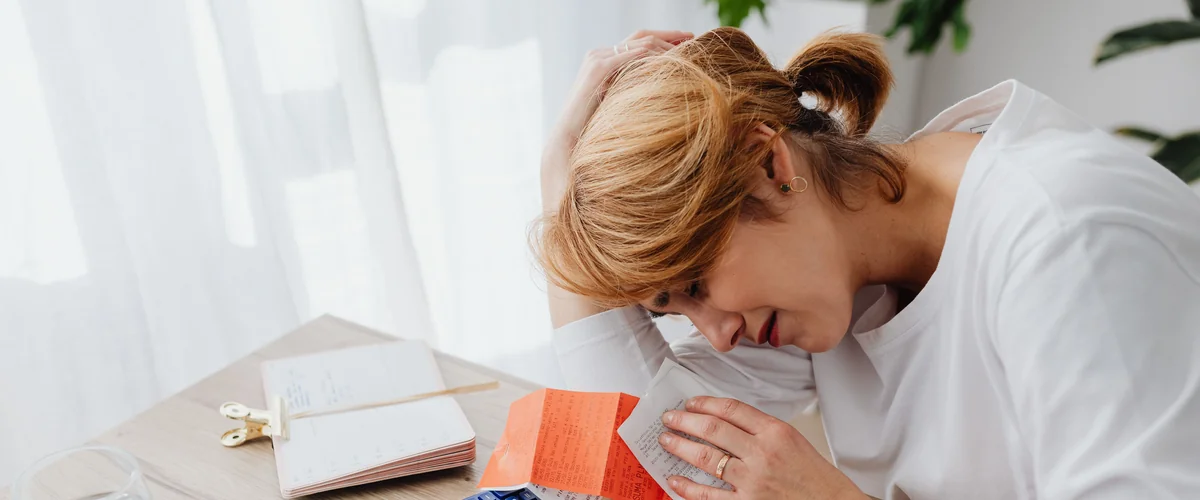 Woman stressed by payday loan debt trap — bills, calculator, financial struggle